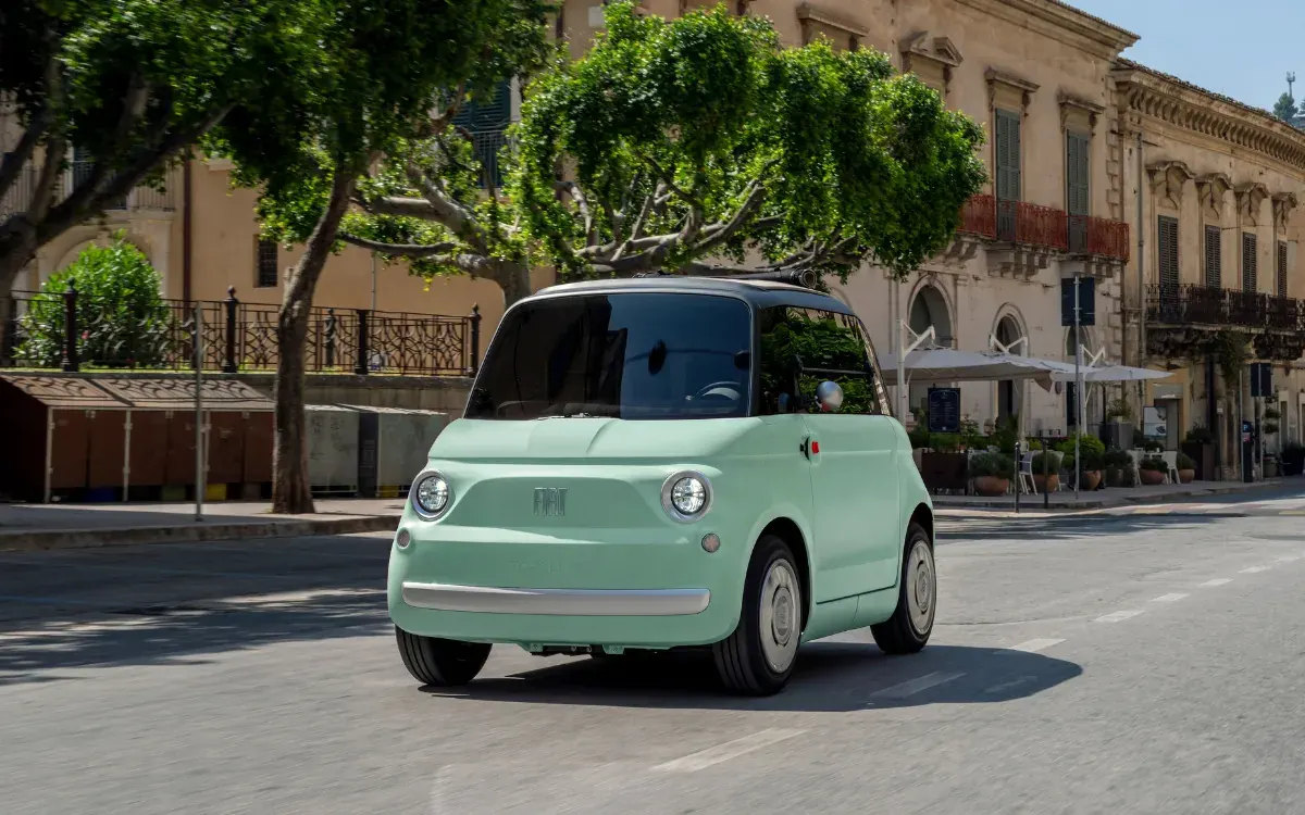 Mintgrüner Fiat Topolino fährt durch eine Altstadt