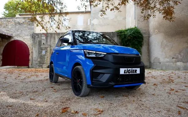 Blauer Ligier JS60 mit schwarzer Front in einem Hof mit Herbstlaub