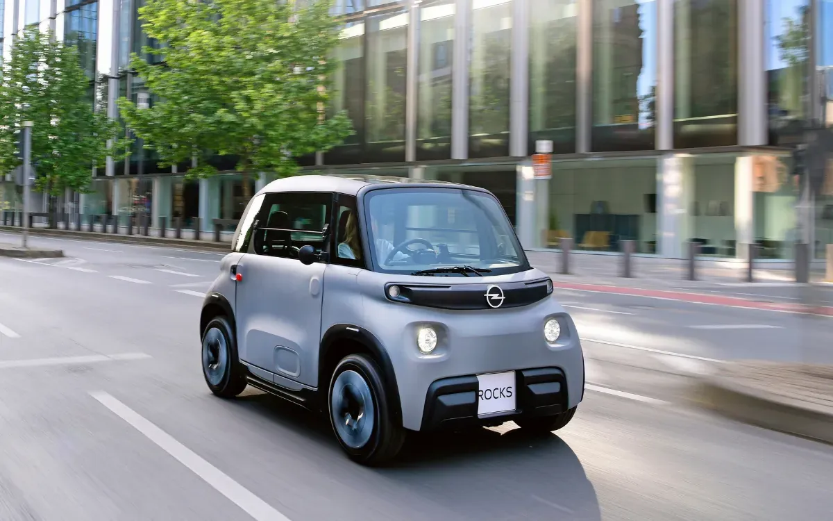Grauer Opel Rocks fährt durch eine Stadtstraße, schräg von vorne